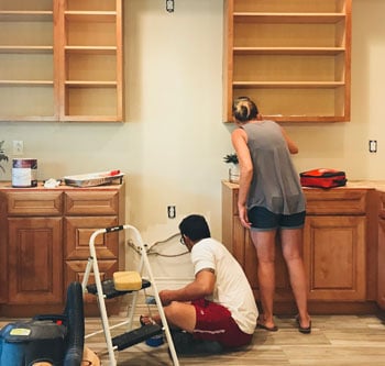 Woman and man painting their kitchen wall together