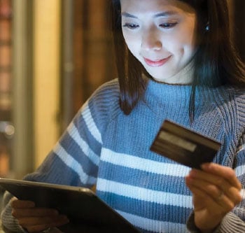 Woman looking at tablet and holding her credit card