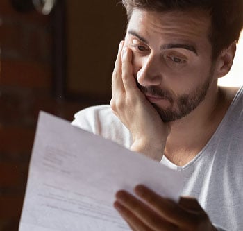 Man looking stressed and staring at a piece of paper